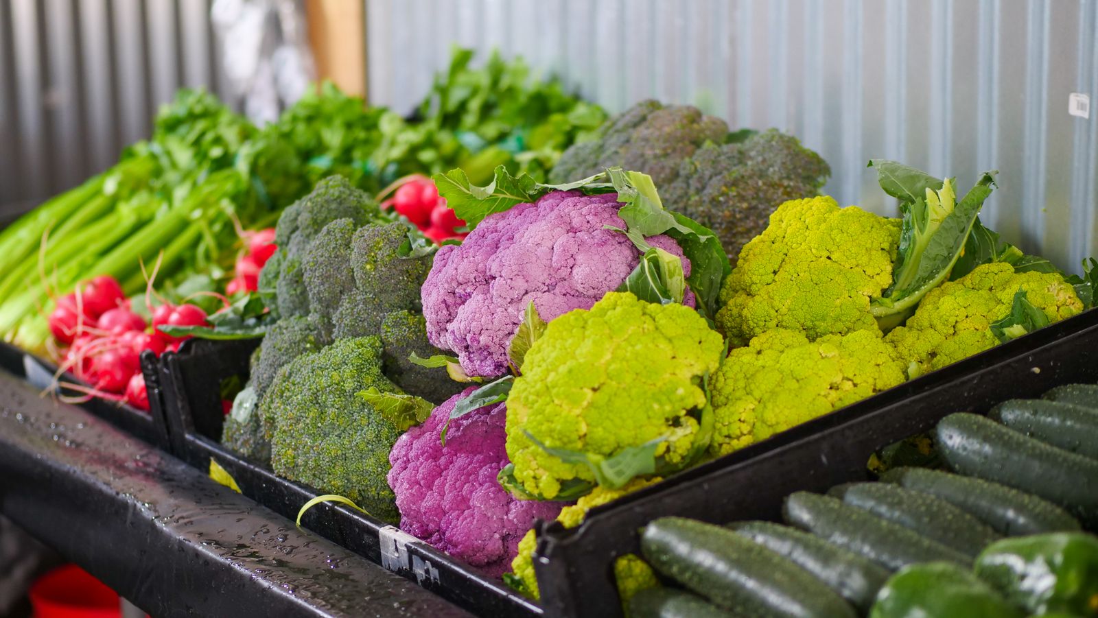 Crates of cauliflower, broccoli and greens at a market stall