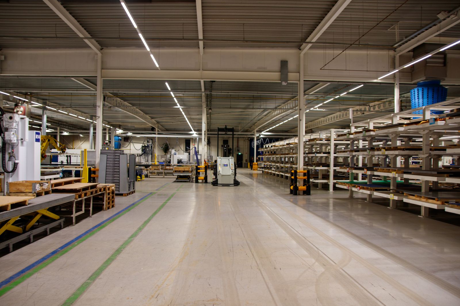 A long, empty distribution hall with painted walkway lines and racking on the right