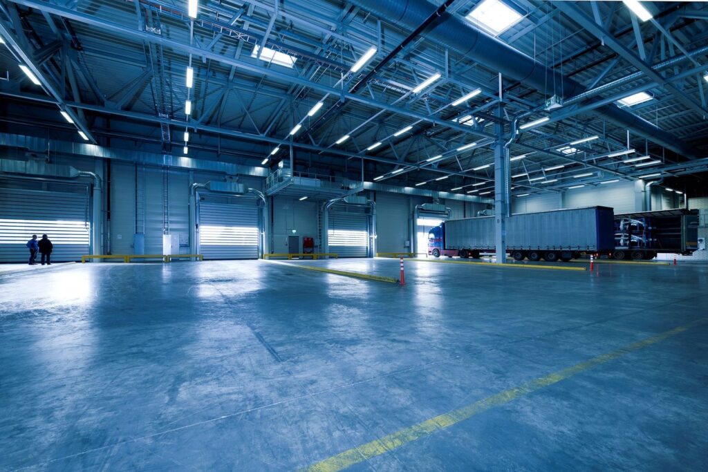 An empty, brightly lit loading hall with roller doors and one trailer at the far end