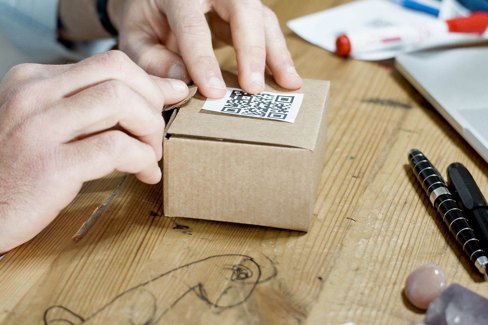 Hands pressing a printed code label onto a small cardboard box