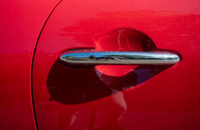 A chrome door handle on deep red paint