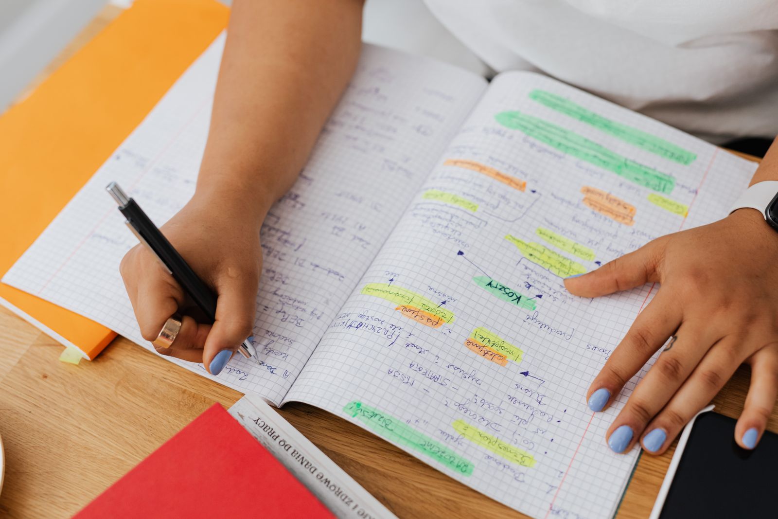 A student's hands highlighting revision notes in a squared notebook