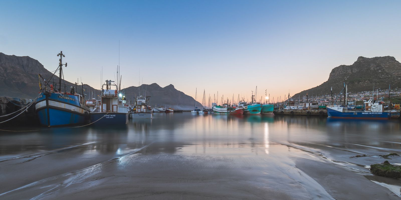 Fishing boats moored in a calm harbour at first light