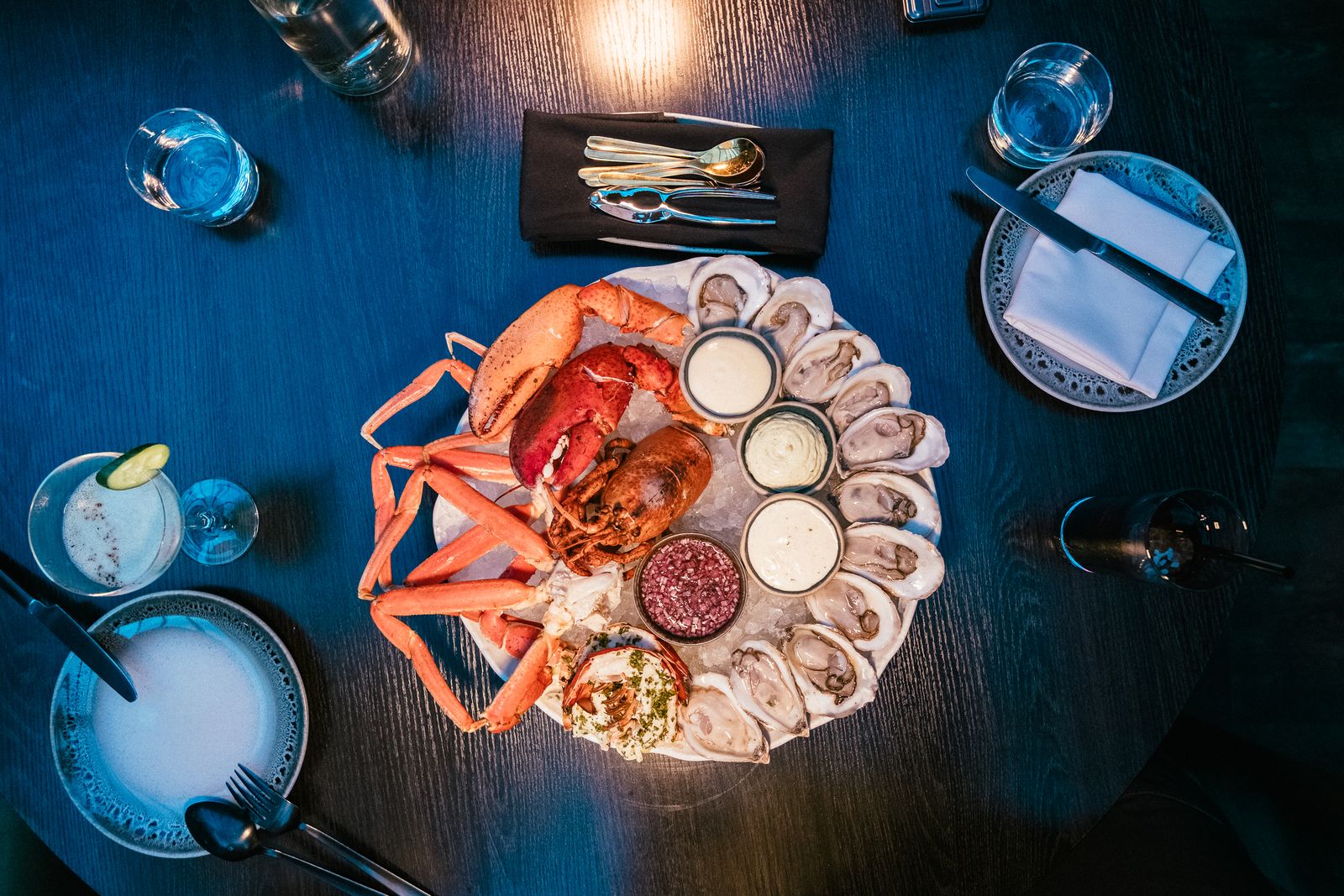 A seafood platter of lobster, crab claws and oysters on ice, seen from above