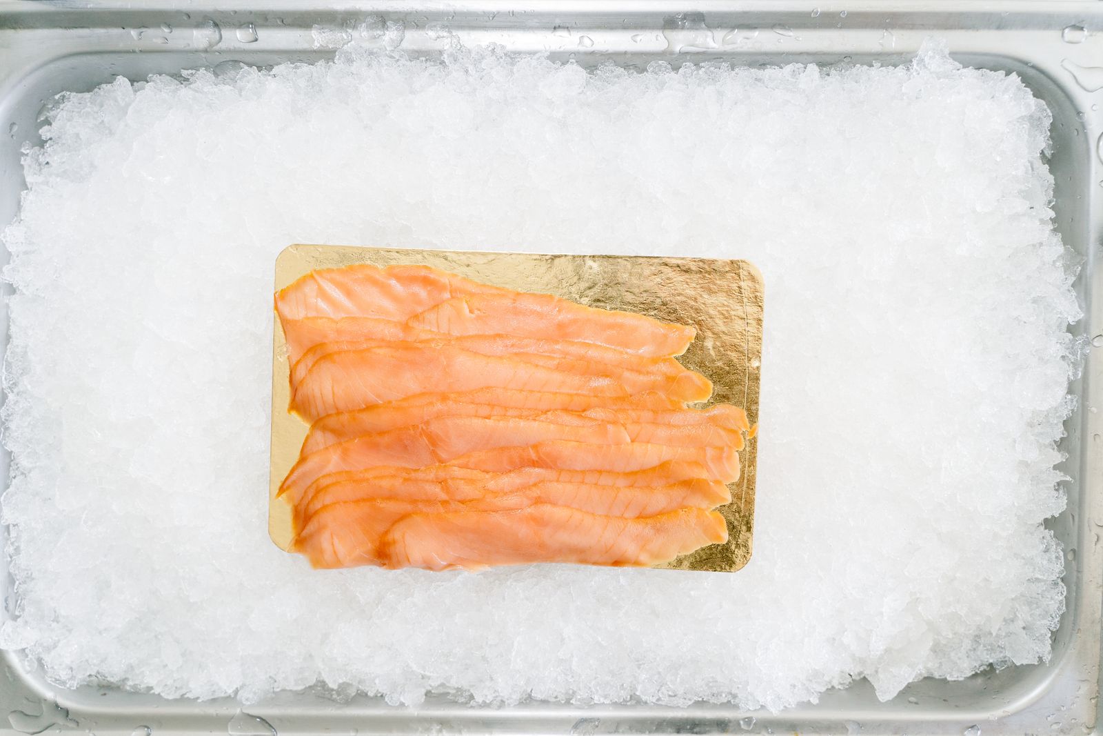 Slices of smoked salmon on a board set in crushed ice