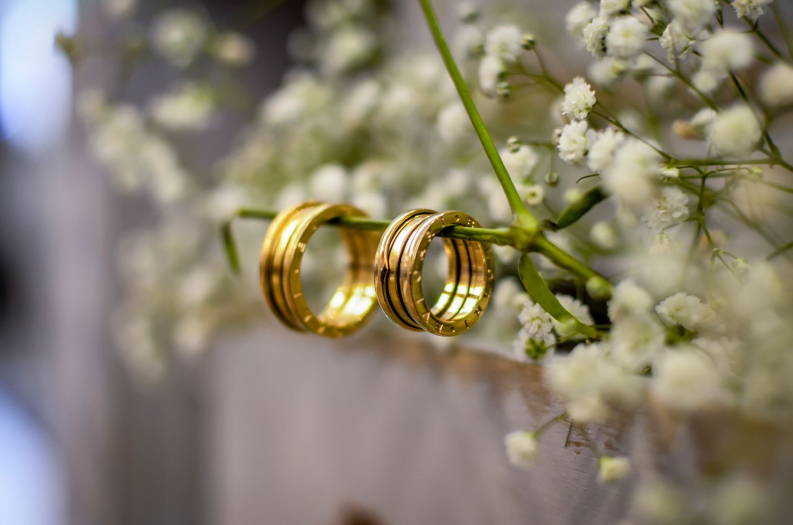 Two gold wedding bands hanging on a stem of baby's breath