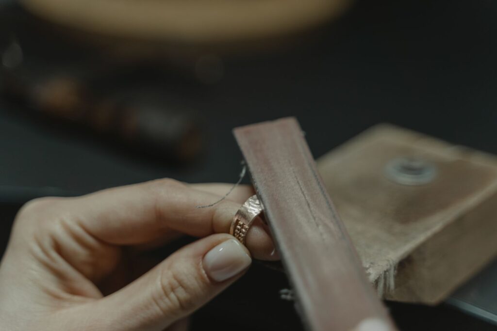 A file smoothing the edge of a textured rose-gold band