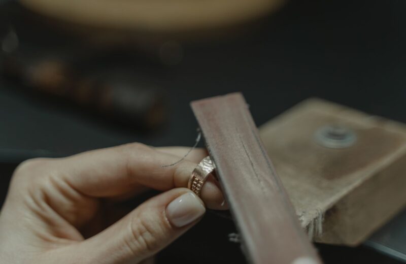 A file smoothing the edge of a textured rose-gold band