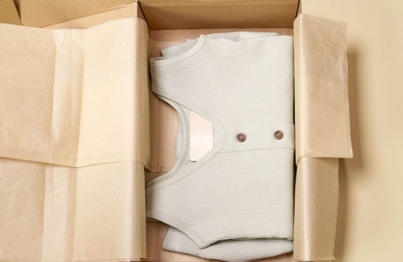 A ribbed garment folded in a cardboard box with paper