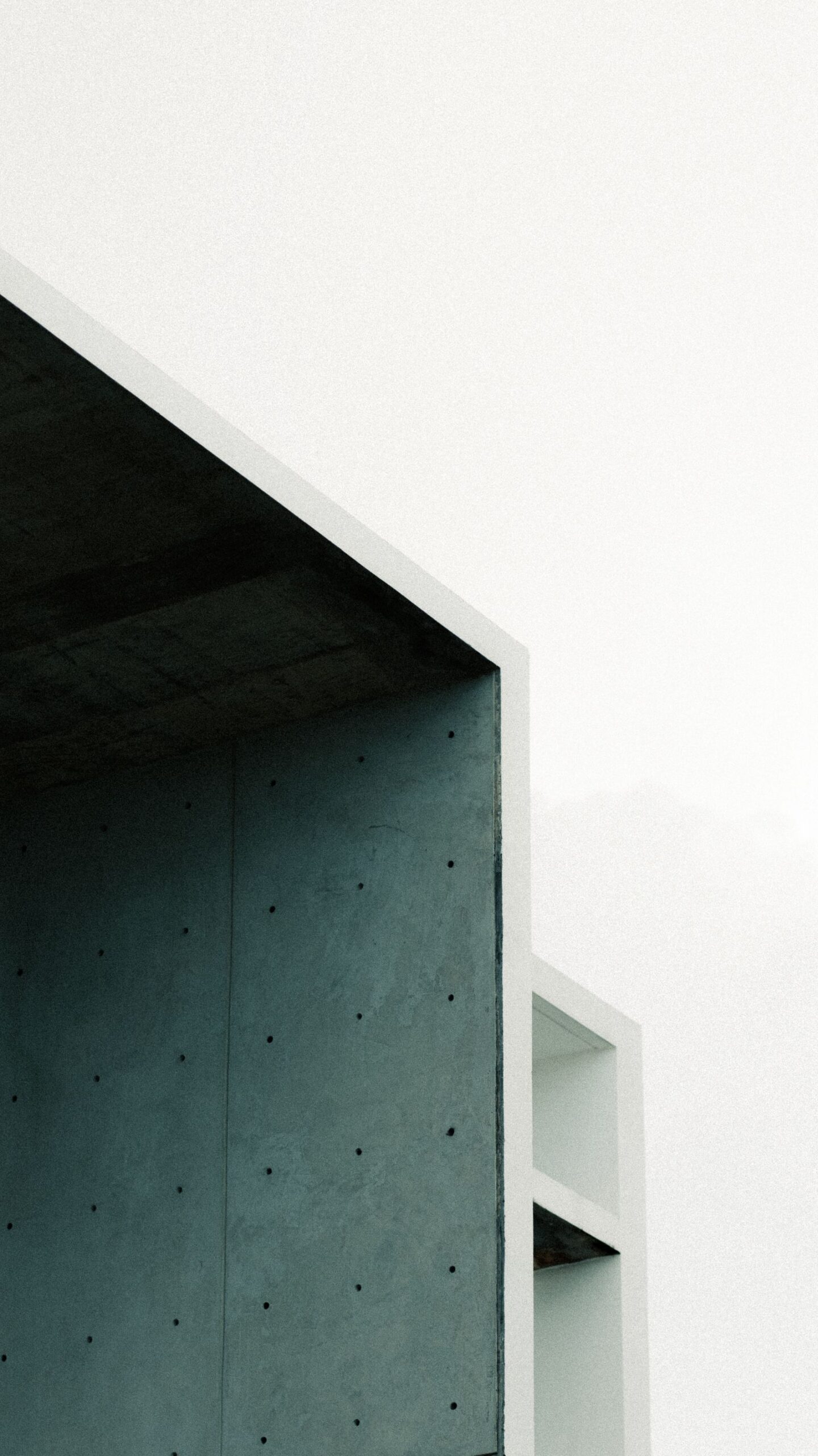 A white concrete building with clean lines against a pale sky, seen from below