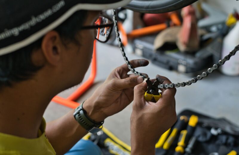 A mechanic working on a bicycle chain with tools on the bench
