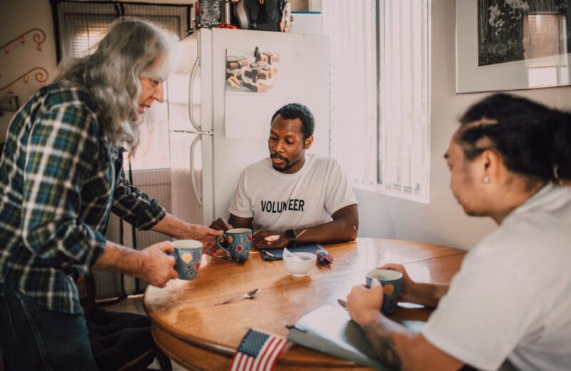 Three people talking over coffee around a kitchen table