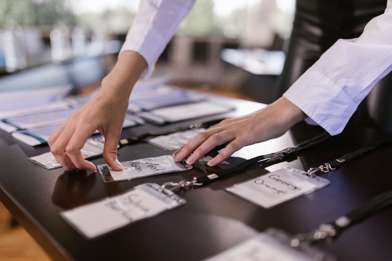 Hands laying out name badges and lanyards on a registration table