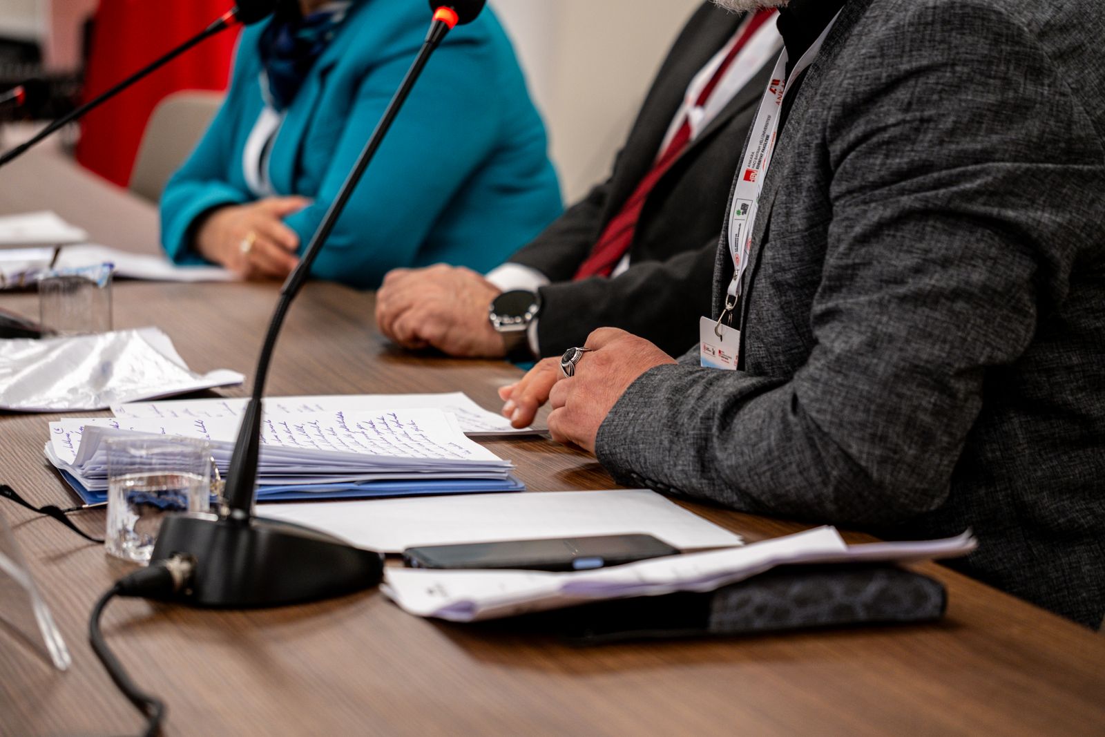 Committee members discussing papers at a meeting table with microphones