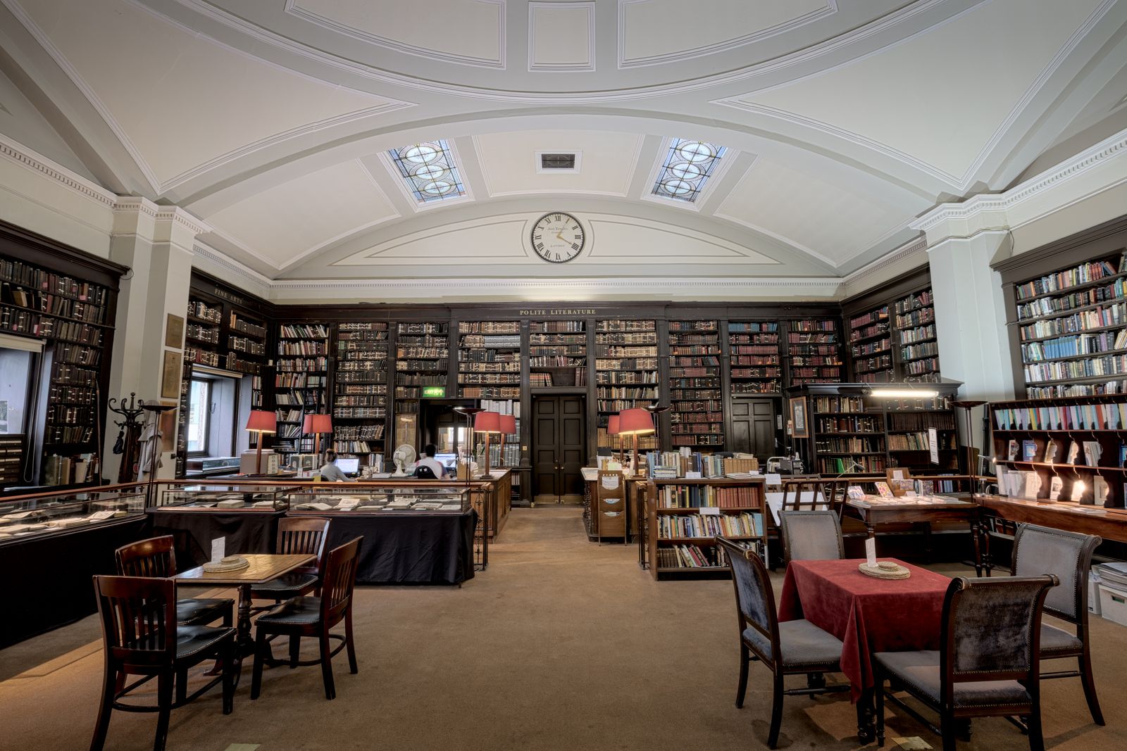 A historic reading room with bookshelves, tables and lamps