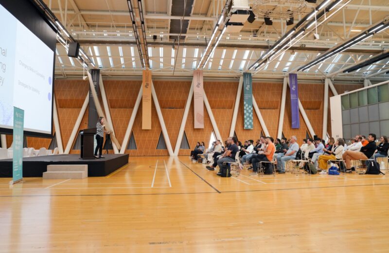 A large conference hall with an audience facing the stage
