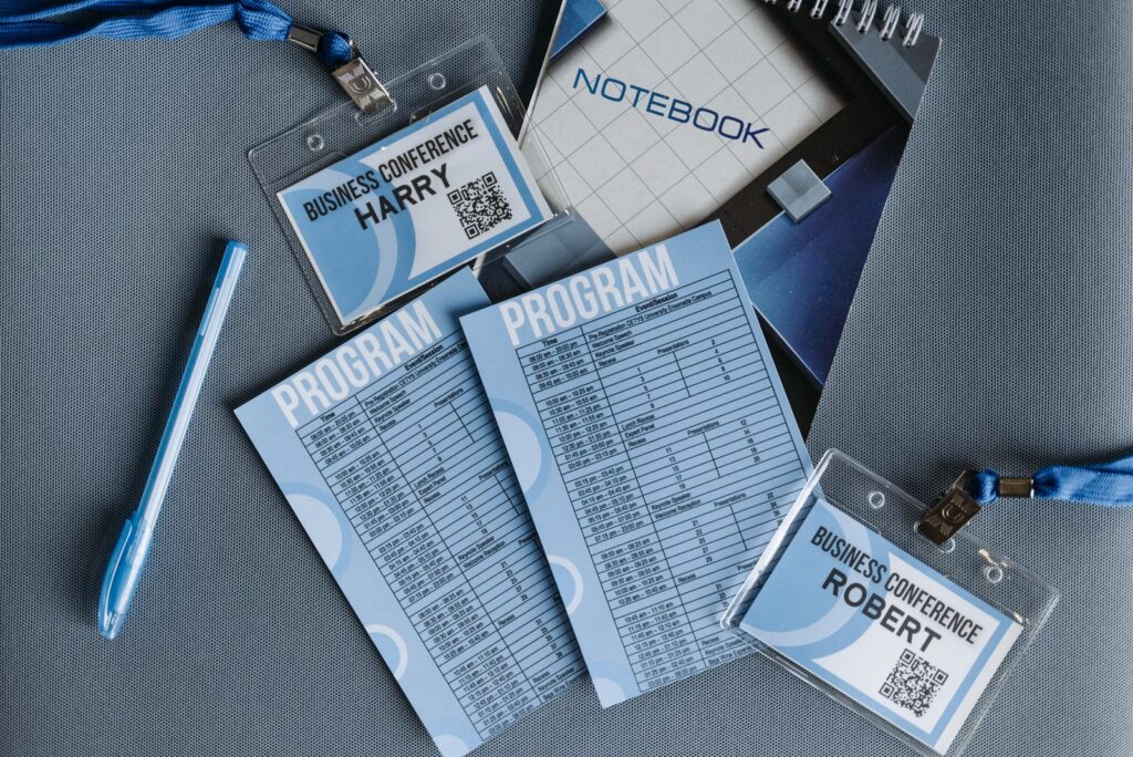 A conference programme, name badges and a pen on a table