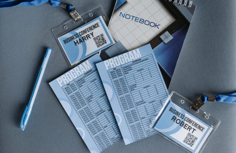 A conference programme, name badges and a pen on a table
