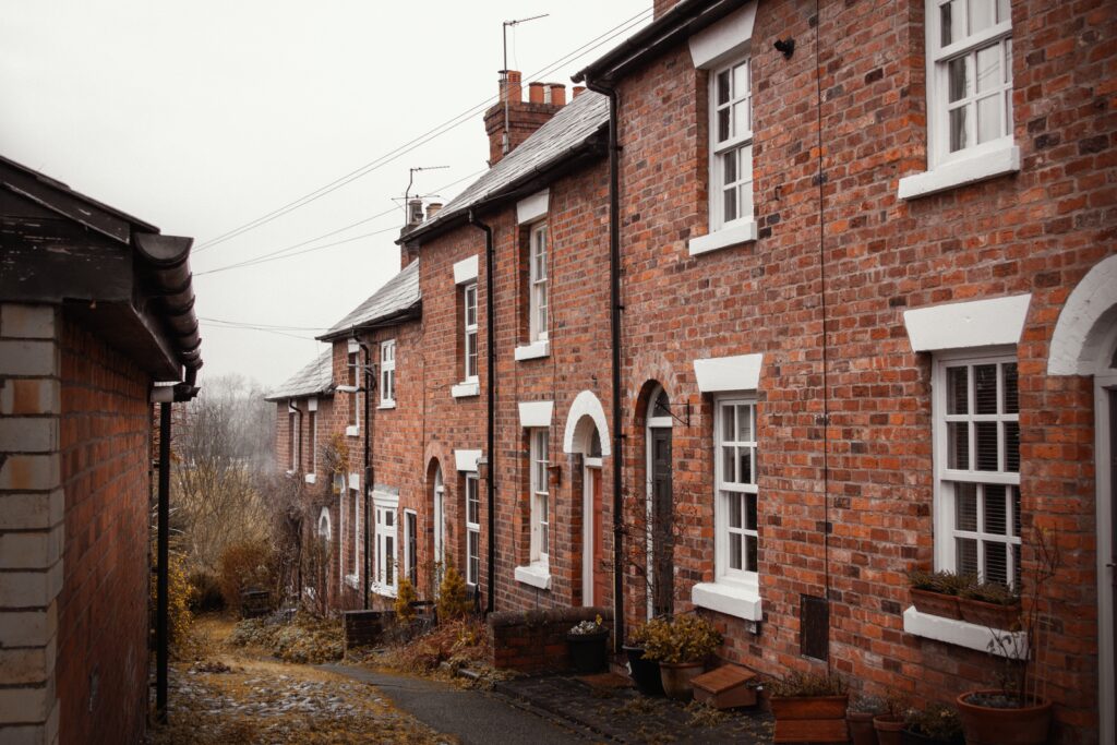 A row of old brick terraced houses along a narrow street