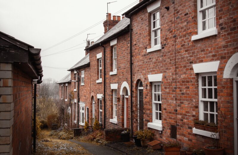 A row of old brick terraced houses along a narrow street