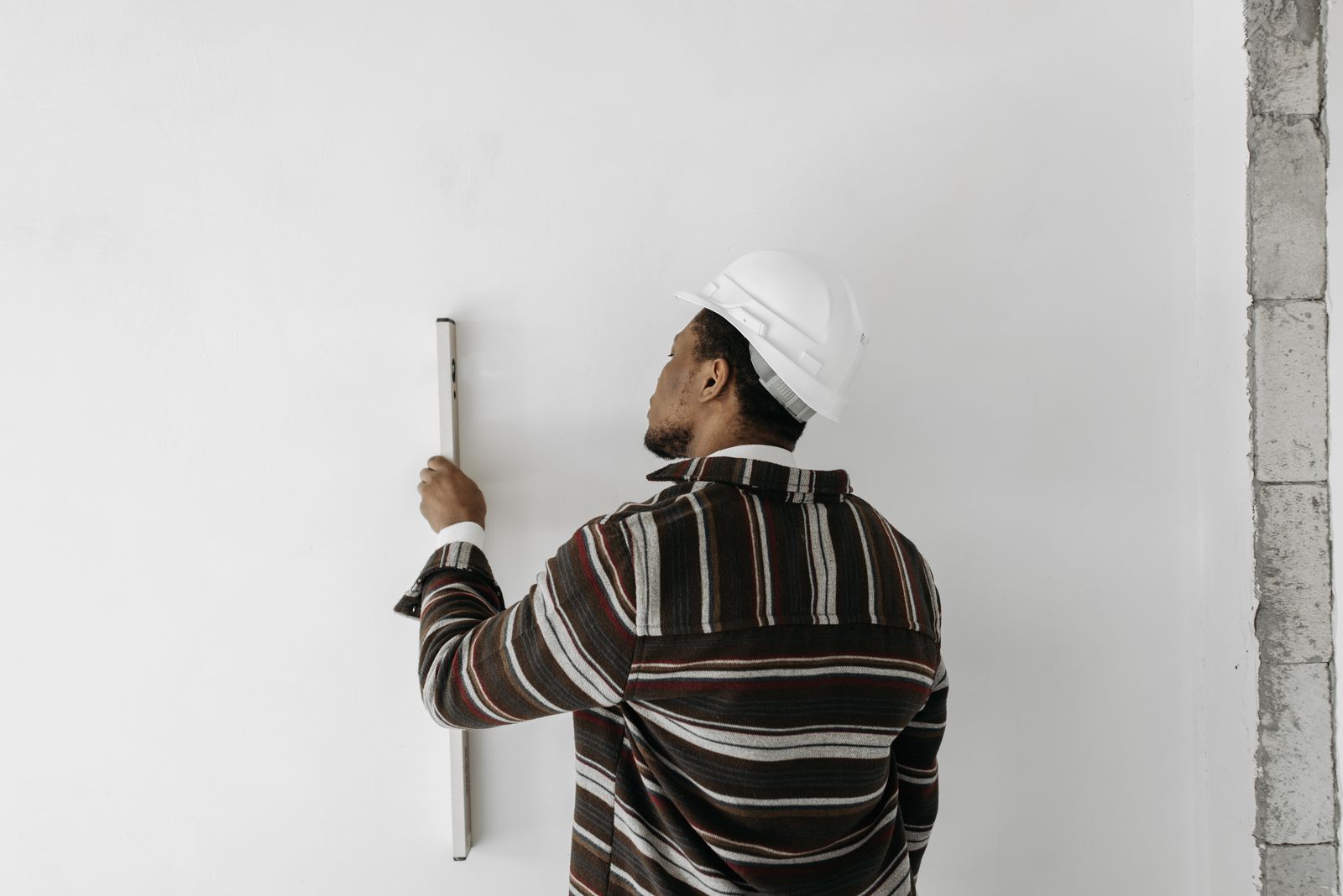 A surveyor, seen from behind, checking a wall with a spirit level