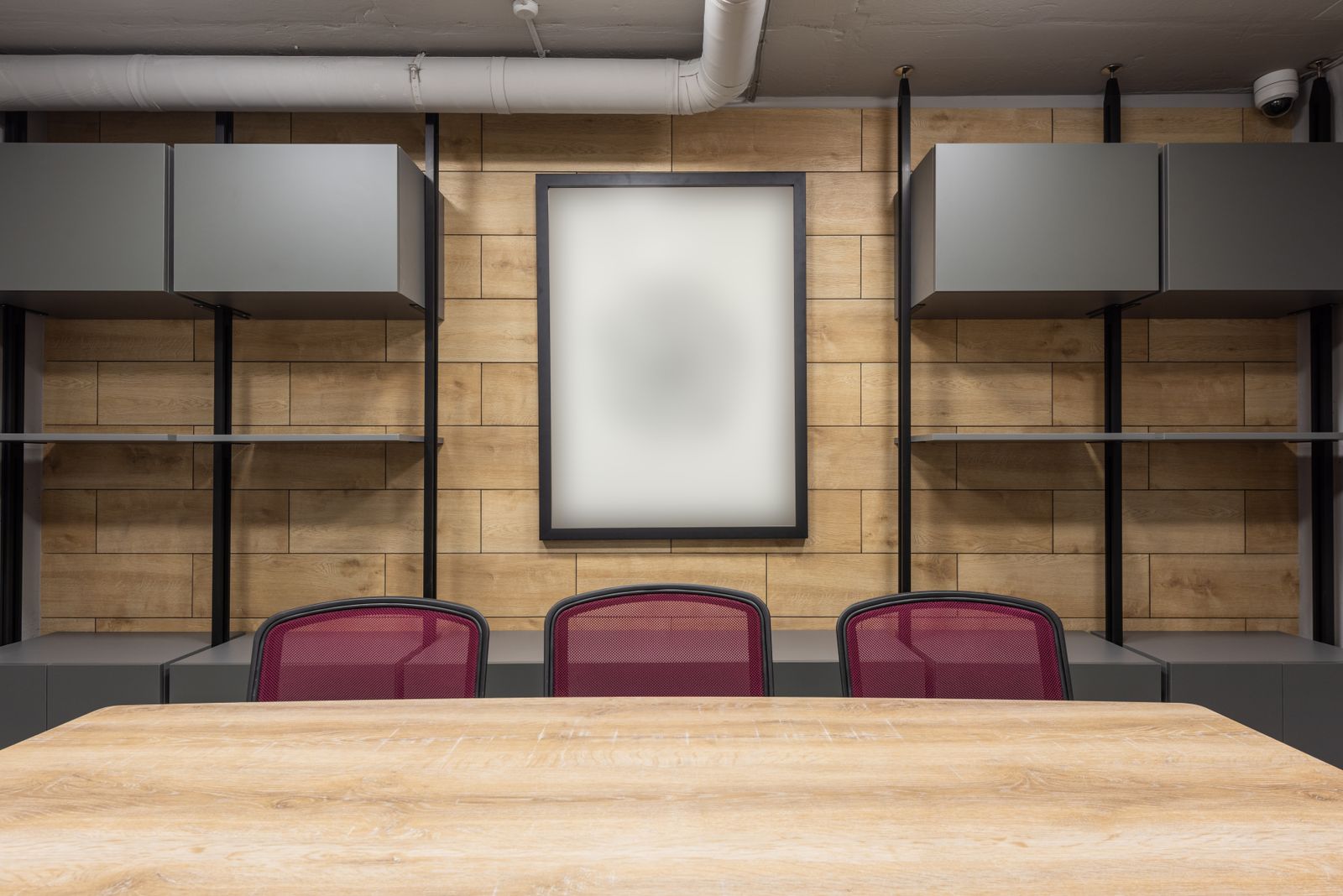A boardroom with a long wooden table and red chairs