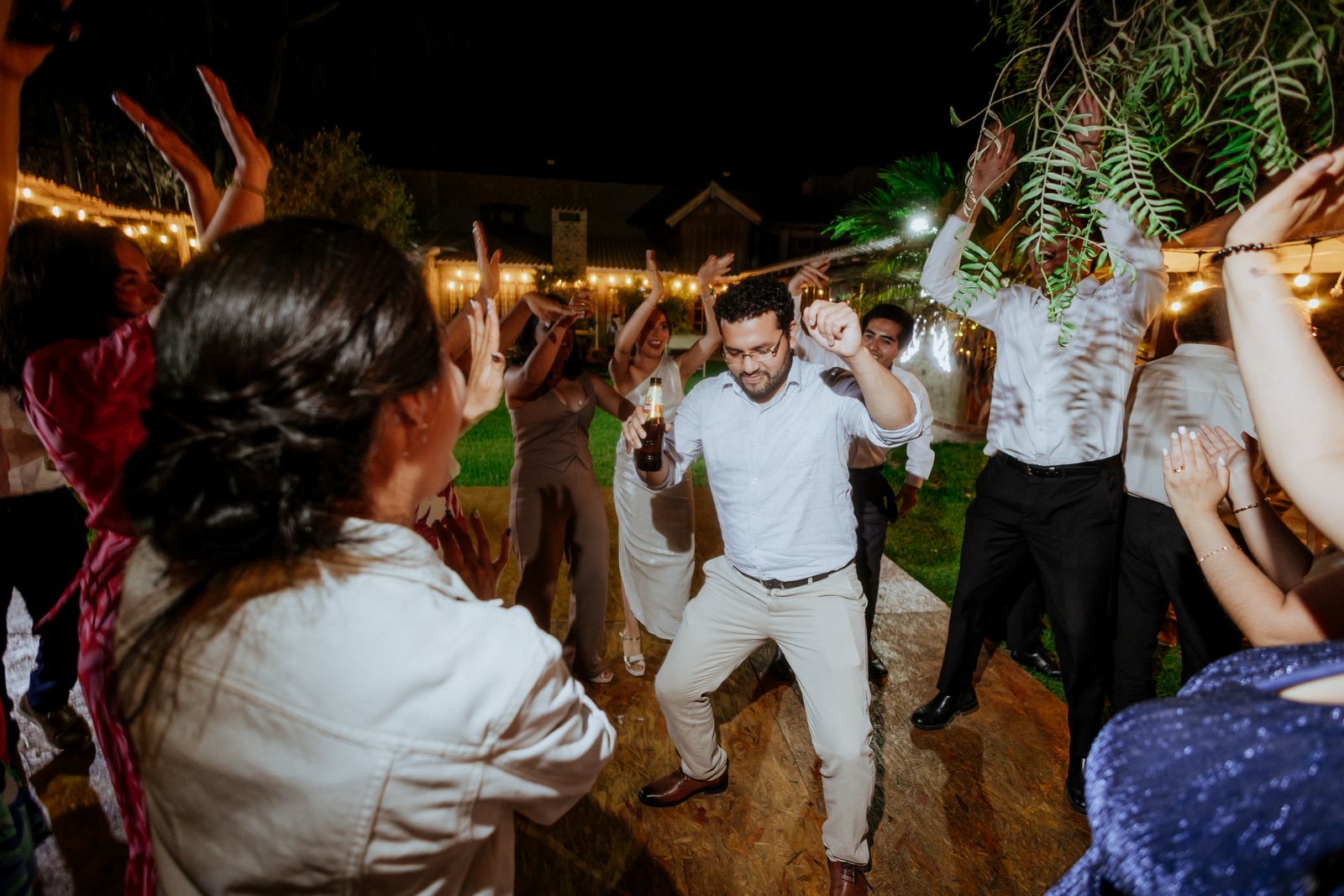 Wedding guests dancing under string lights at an evening reception
