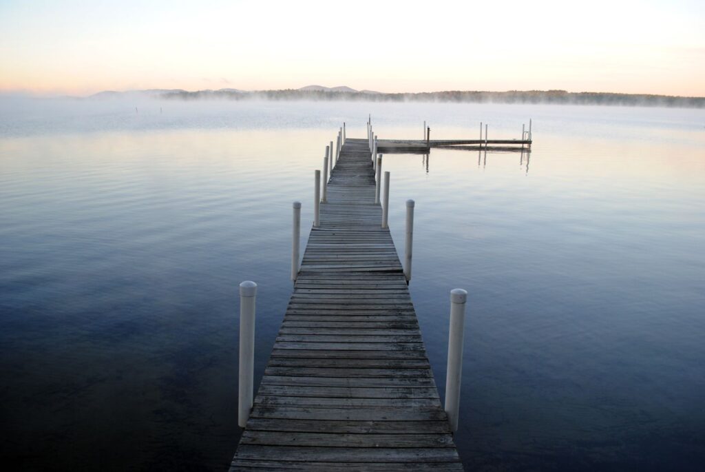A wooden jetty running out into a still lake at dawn