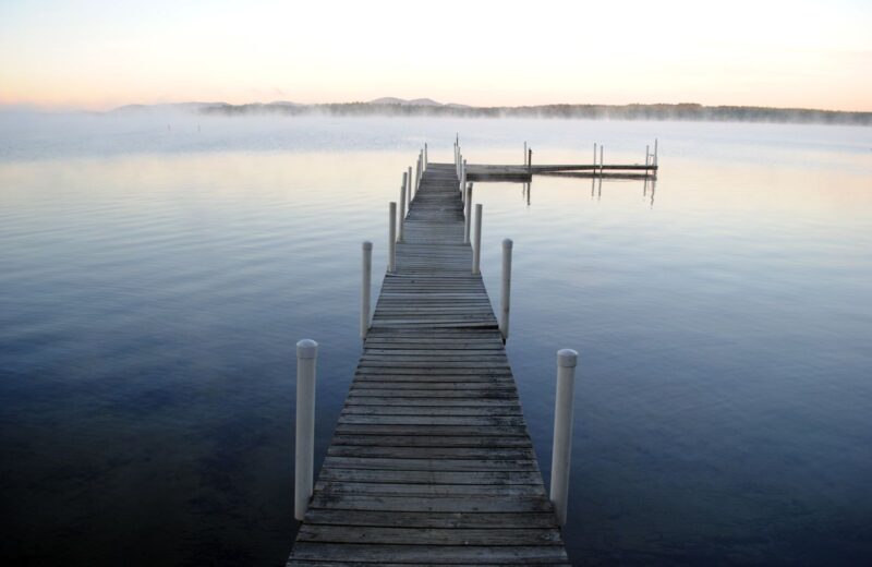 A wooden jetty running out into a still lake at dawn