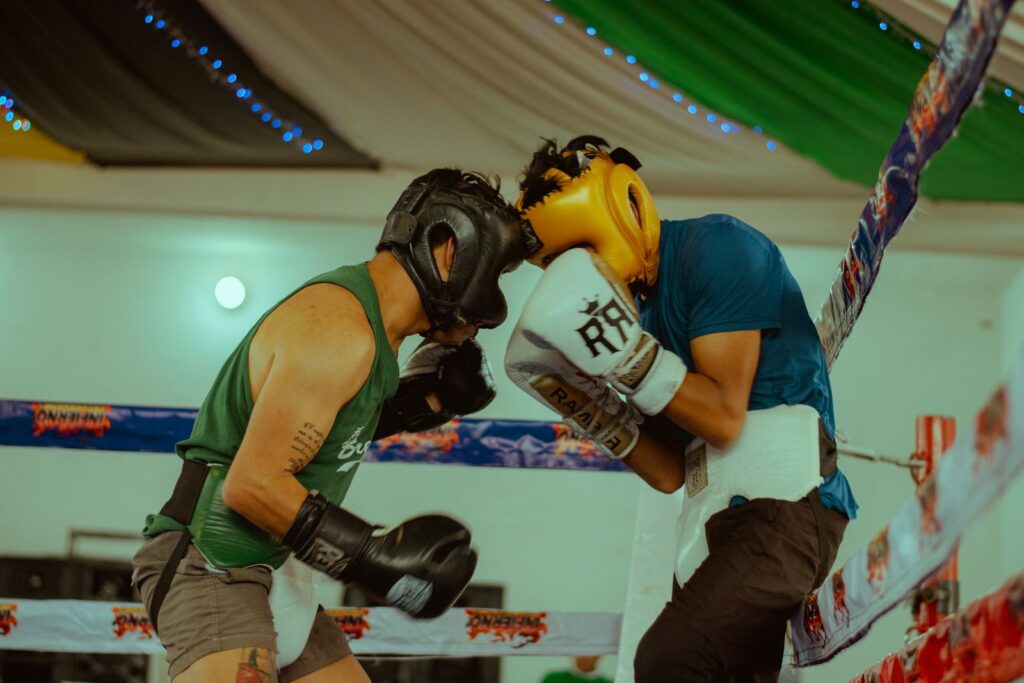 Two boxers in headgear and gloves trading punches at close range in a training ring