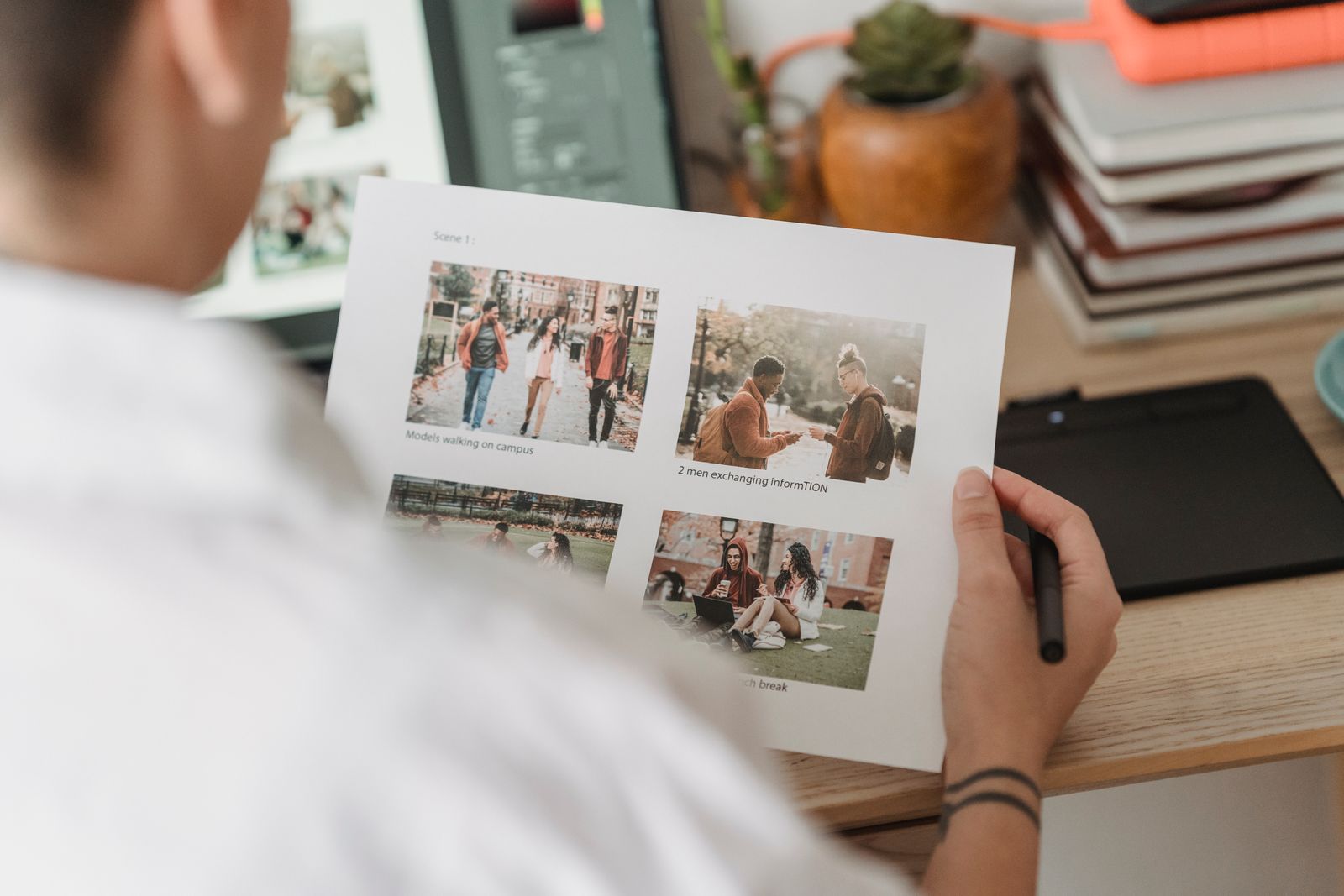 A designer at a table checking a sheet of printed photographs