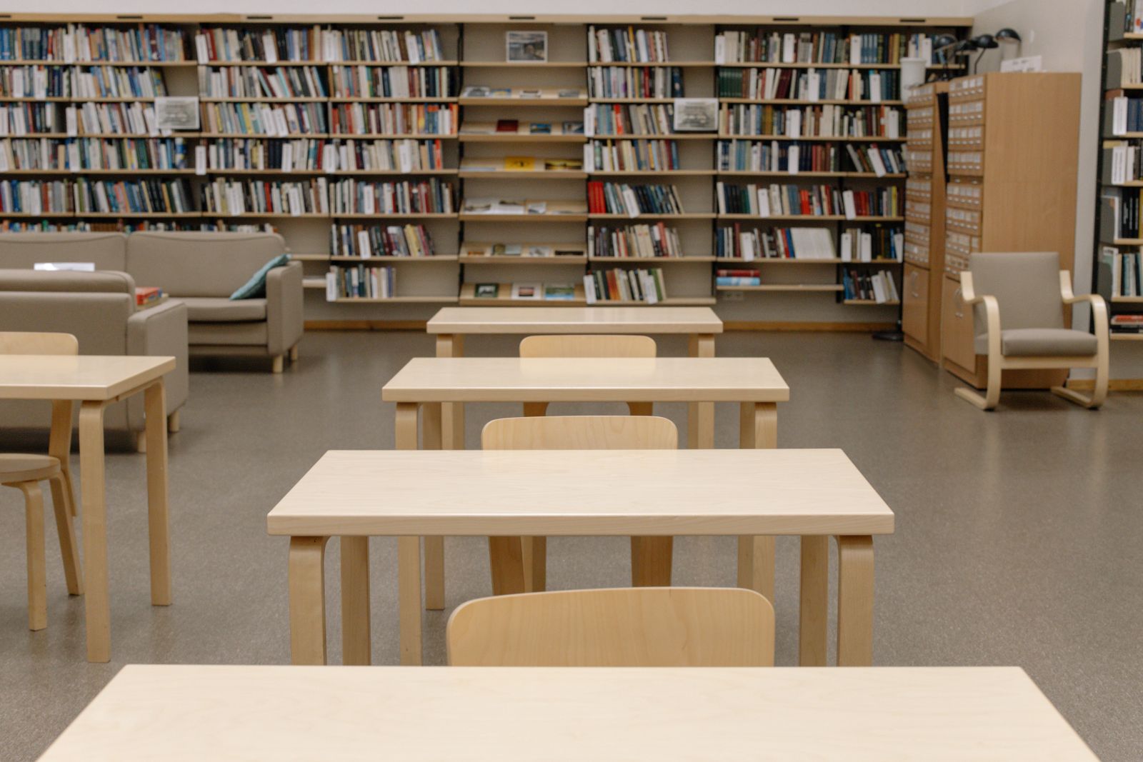 Rows of light wooden reading tables in a quiet library