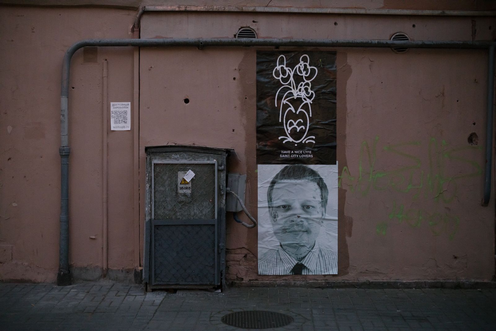 Printed posters pasted on a pink wall next to a grey door