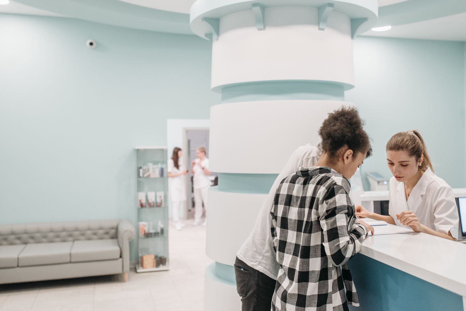 Two staff members working at a bright clinic reception desk