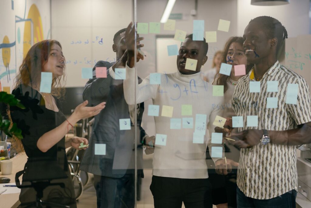 A group of colleagues sorting sticky notes on a glass wall
