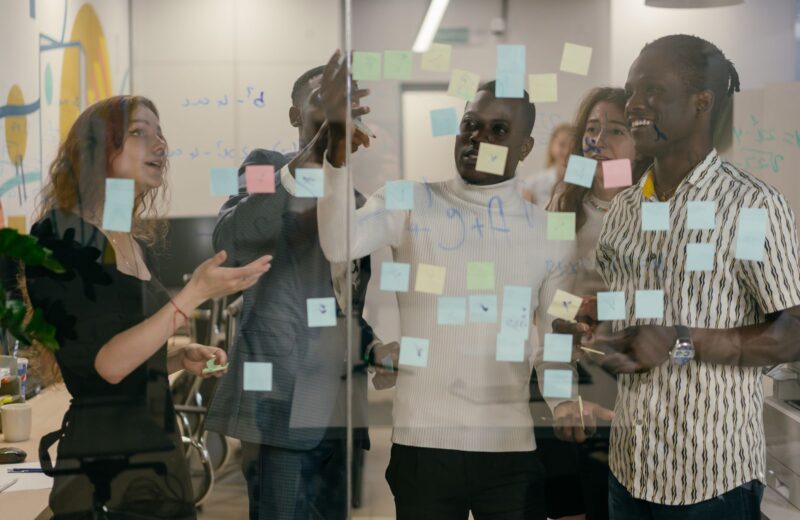 A group of colleagues sorting sticky notes on a glass wall