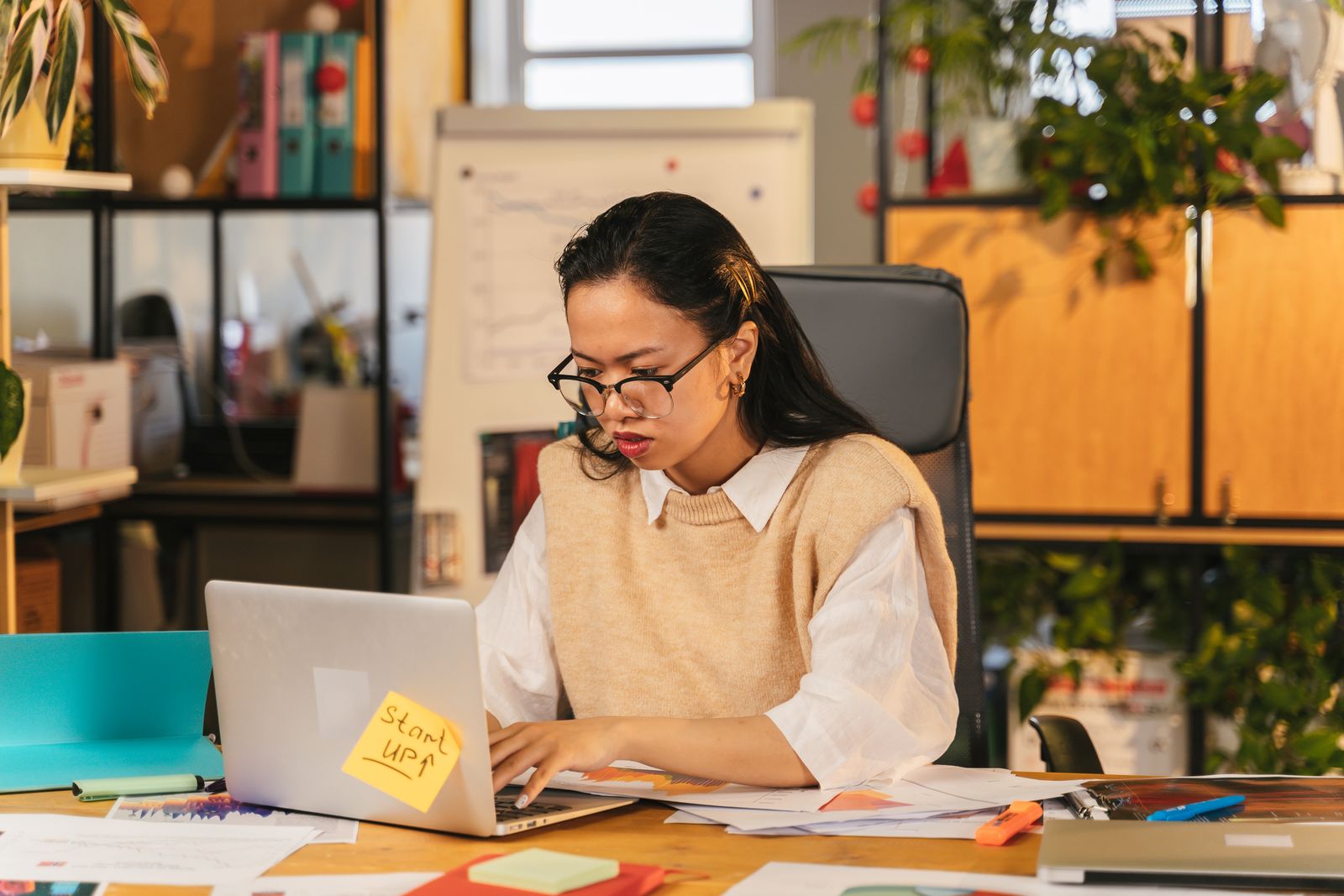 A support engineer with glasses concentrating on her laptop at a desk