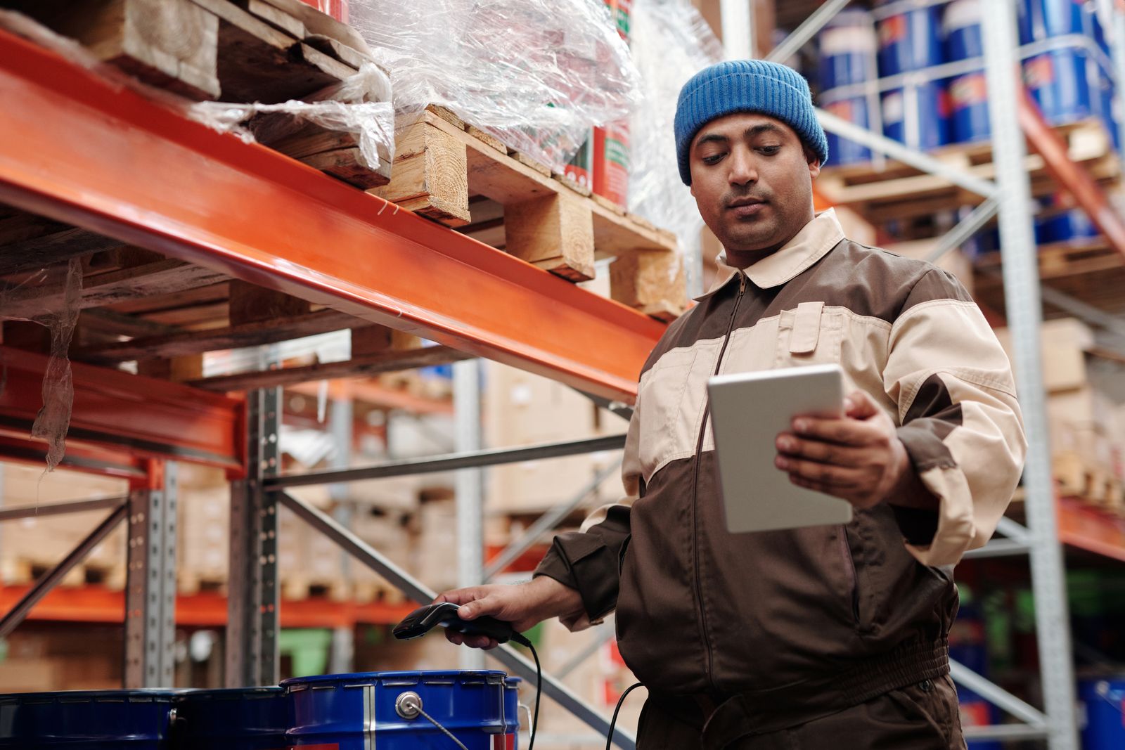 A warehouse worker scanning stock on a tablet between tall shelves