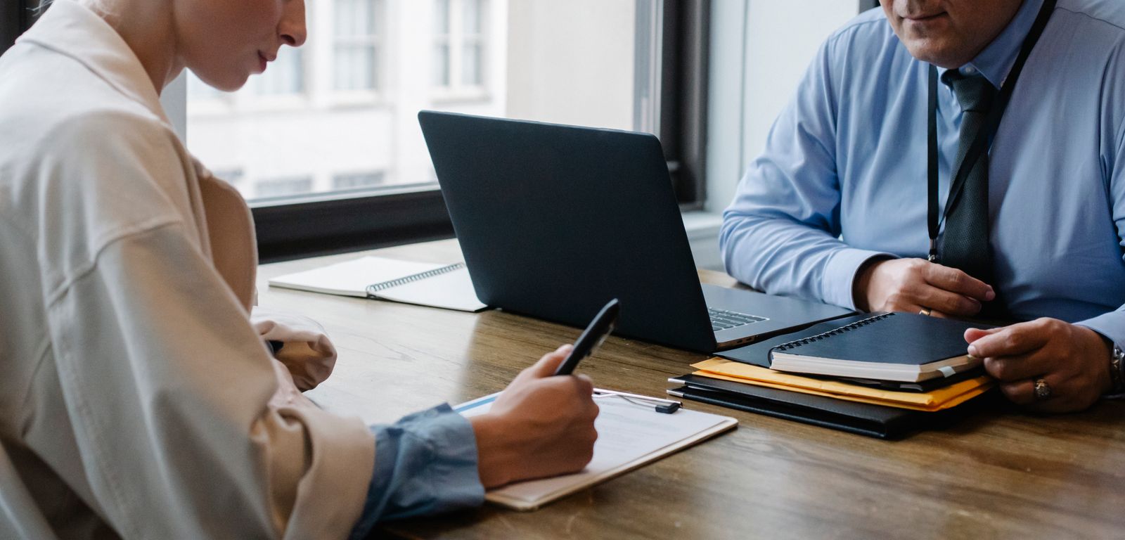A researcher taking notes beside a laptop during a customer interview