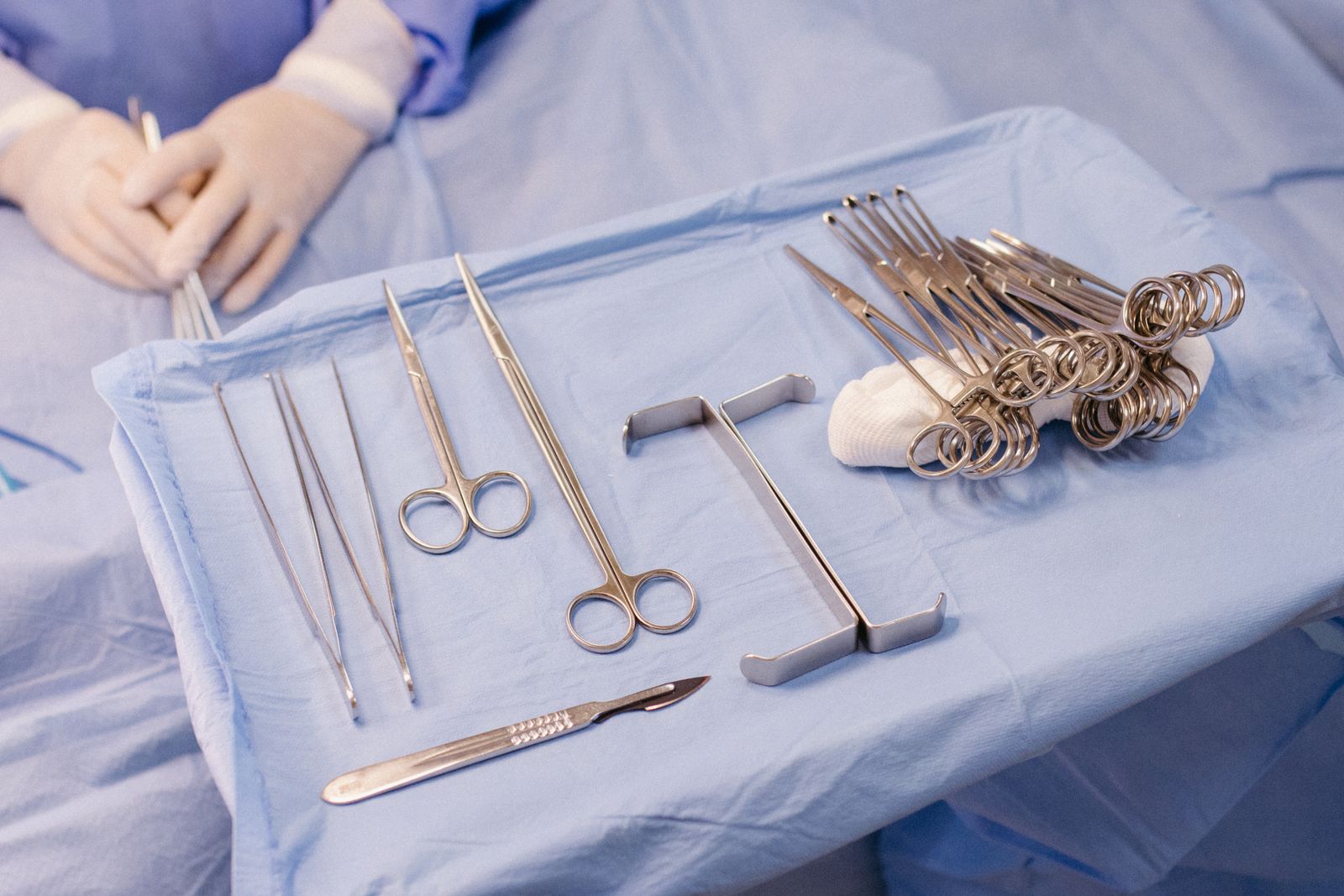 Surgical instruments laid out in a row on a blue sterile drape
