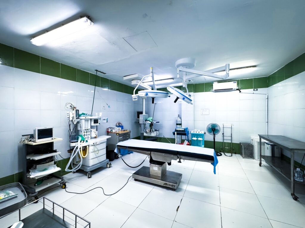 A brightly lit operating theatre with its table and equipment, empty