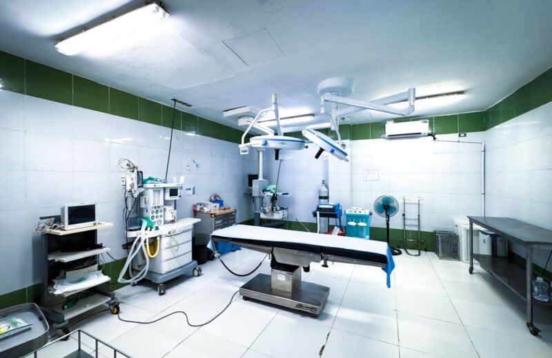 A brightly lit operating theatre with its table and equipment, empty