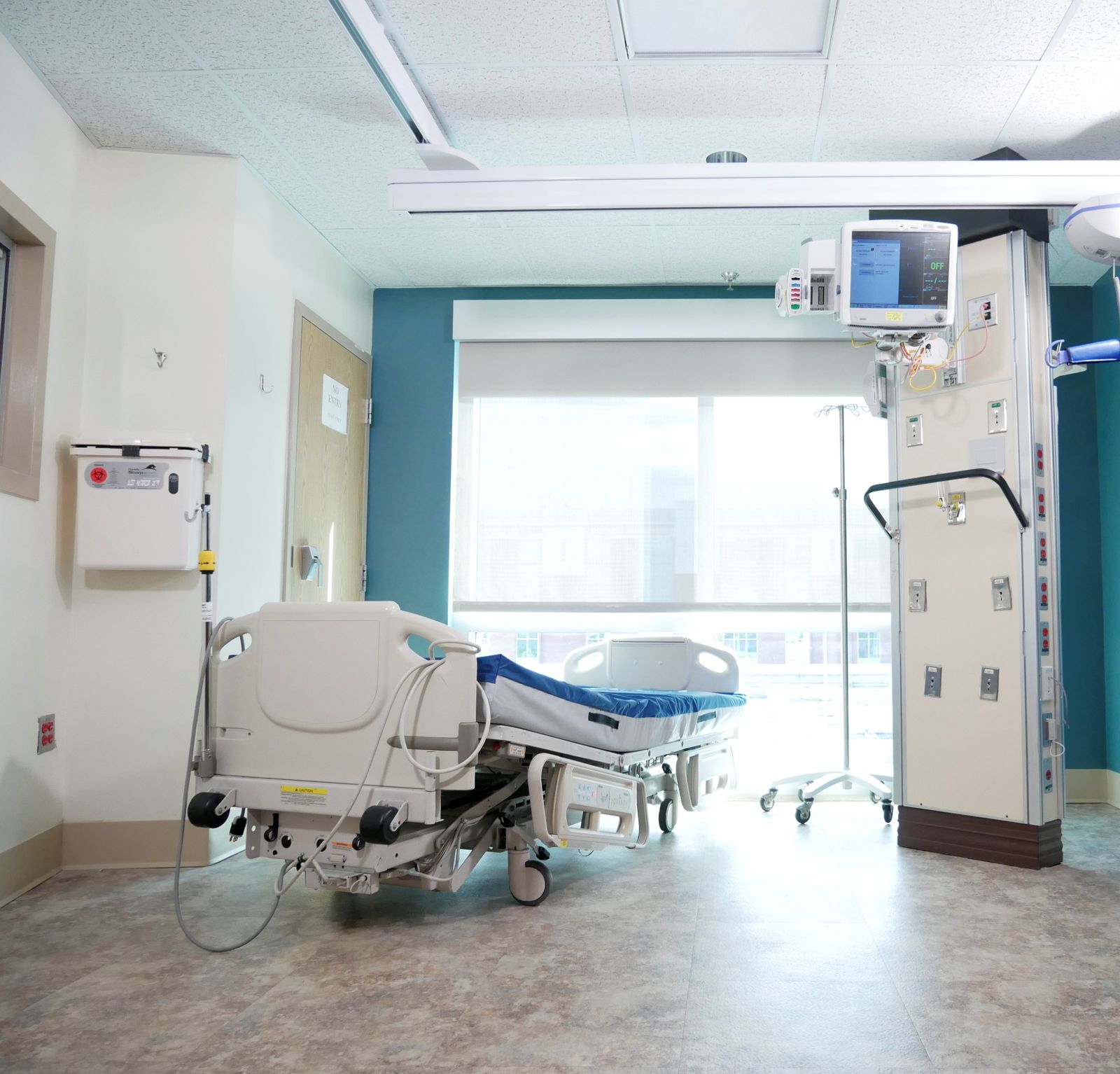 An empty recovery room with an adjustable bed beside a large window
