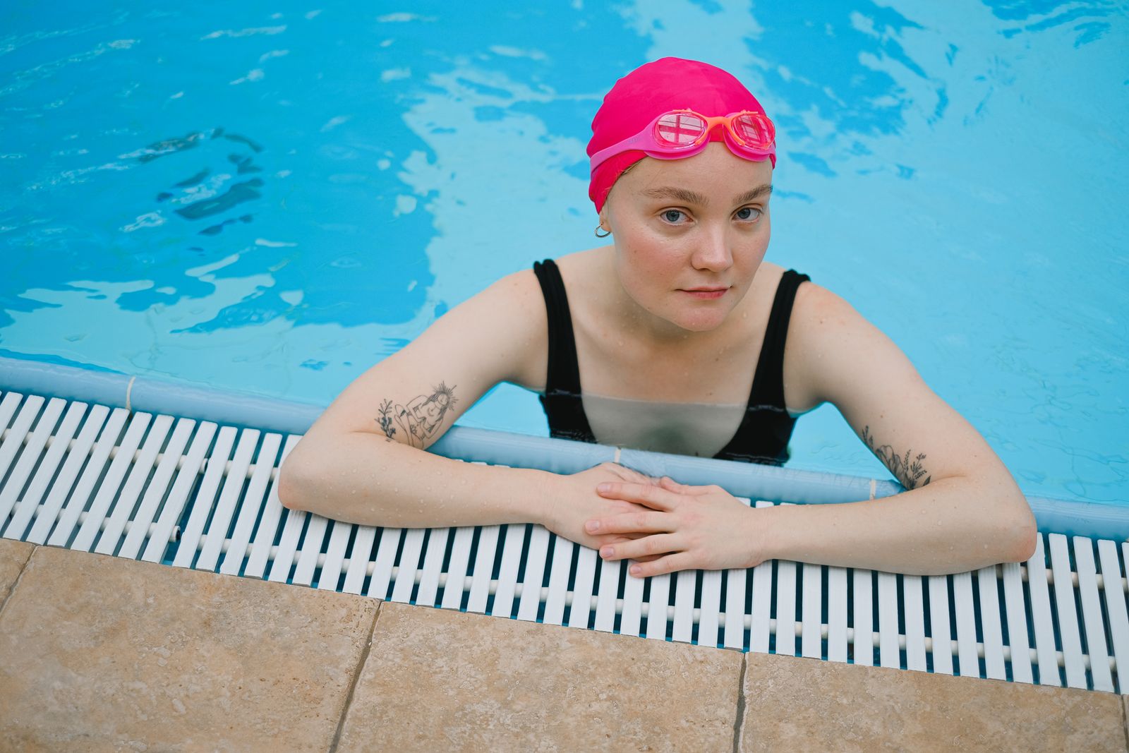 Swimmer resting on the pool edge in a cap and goggles