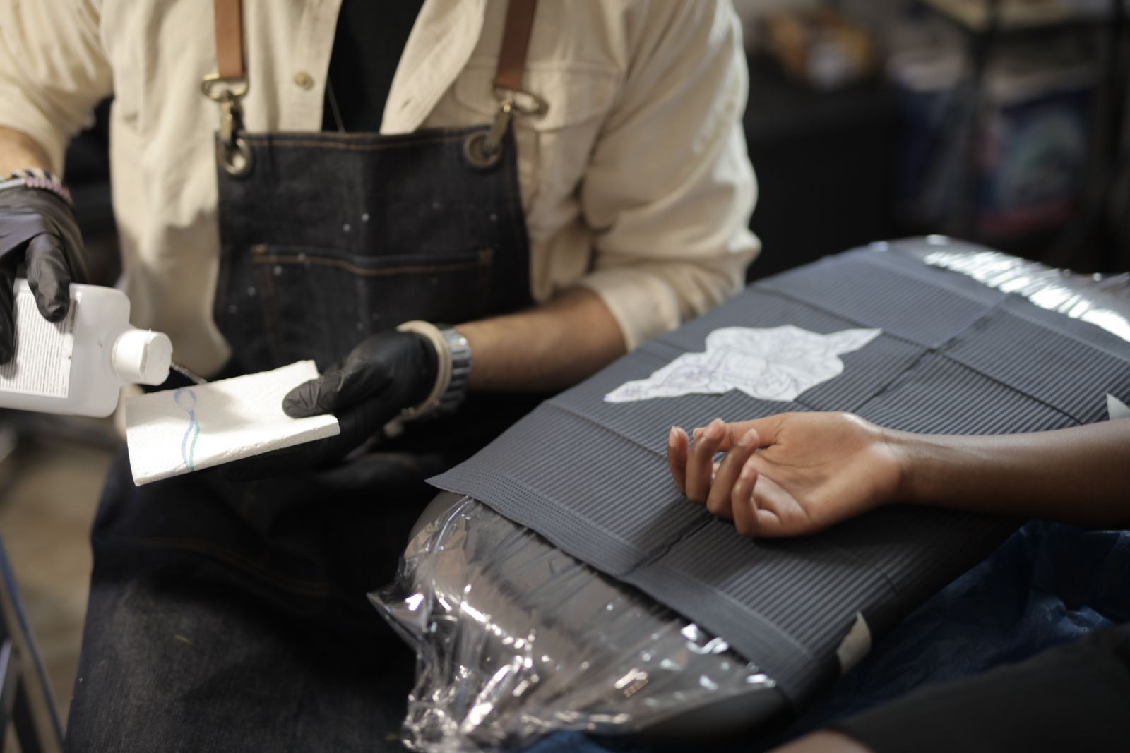 A tattoo artist wiping down the workstation before setting up for a client