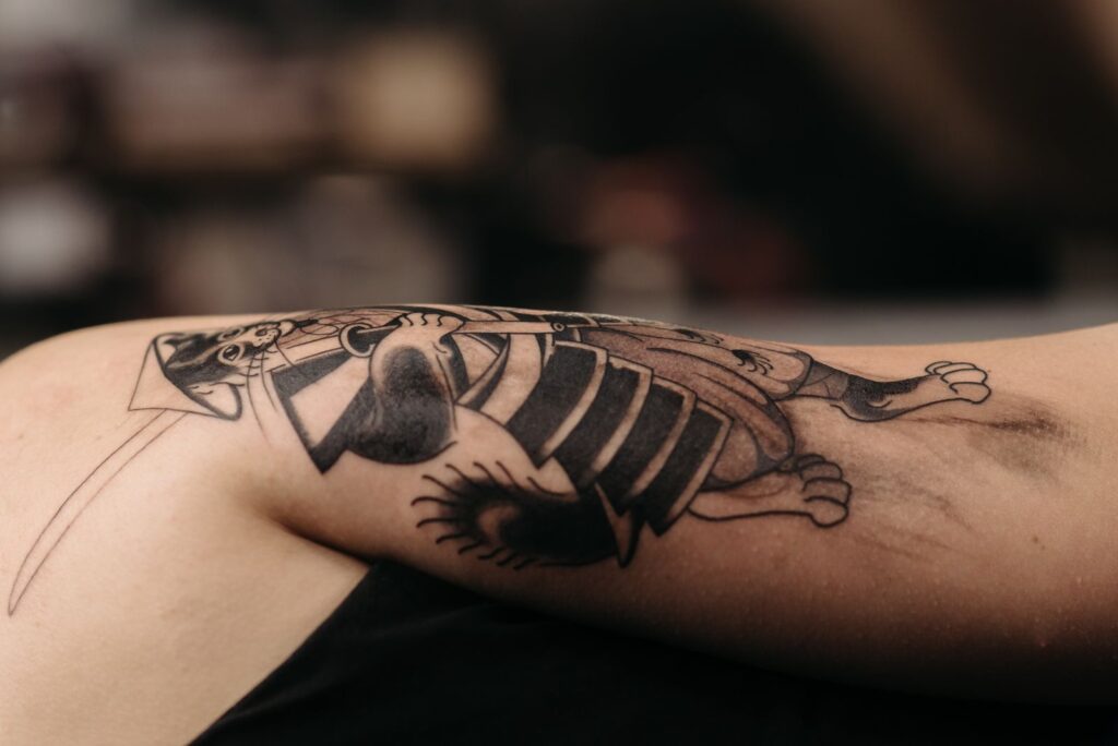 A healed black and grey cat tattoo on an arm