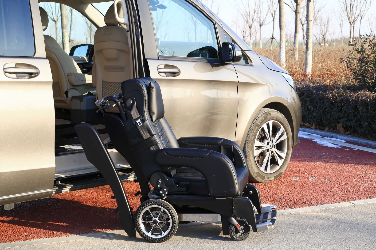 A swivel wheelchair seat lowered beside the open sliding door of a people carrier