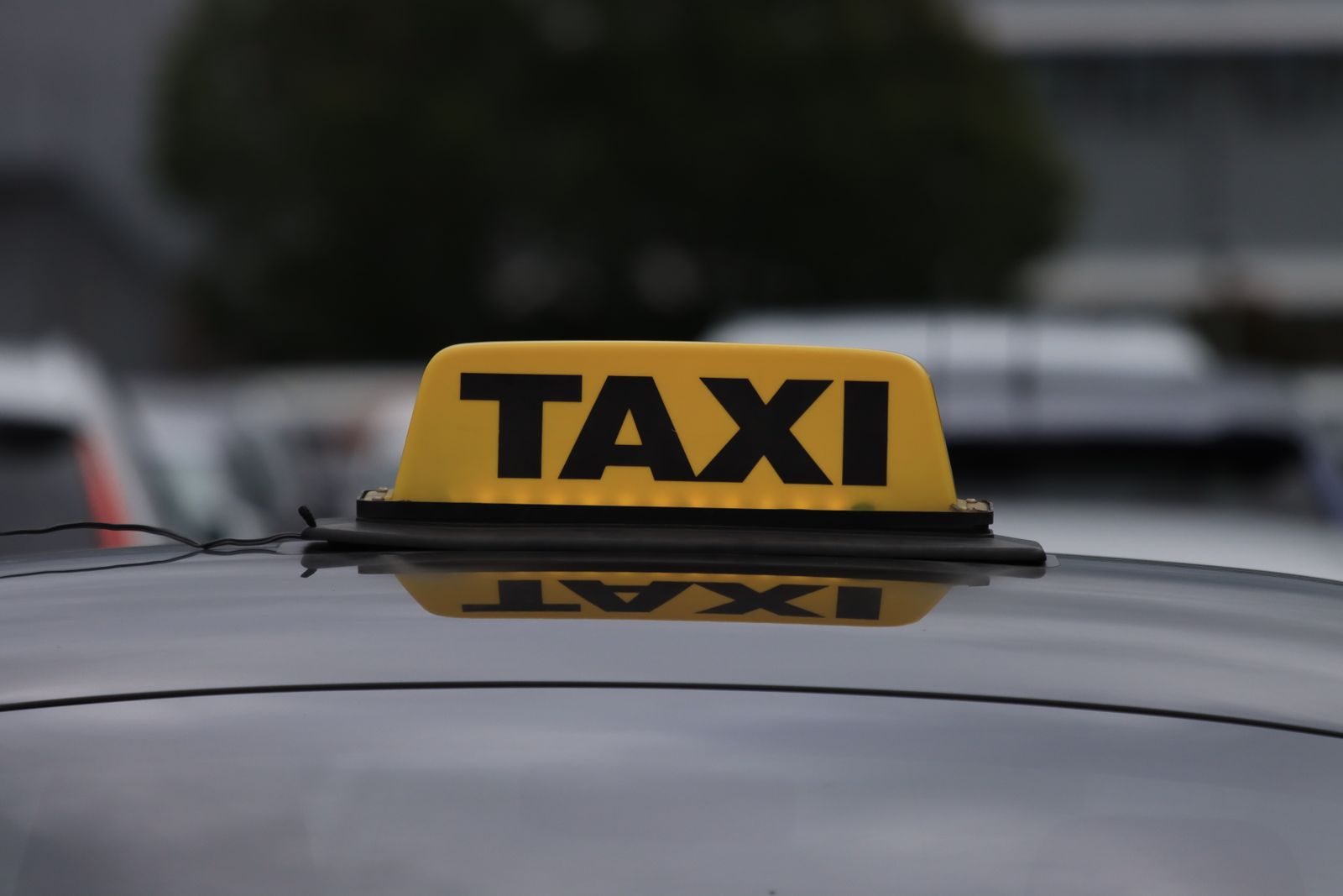 A lit taxi sign on the roof of a car