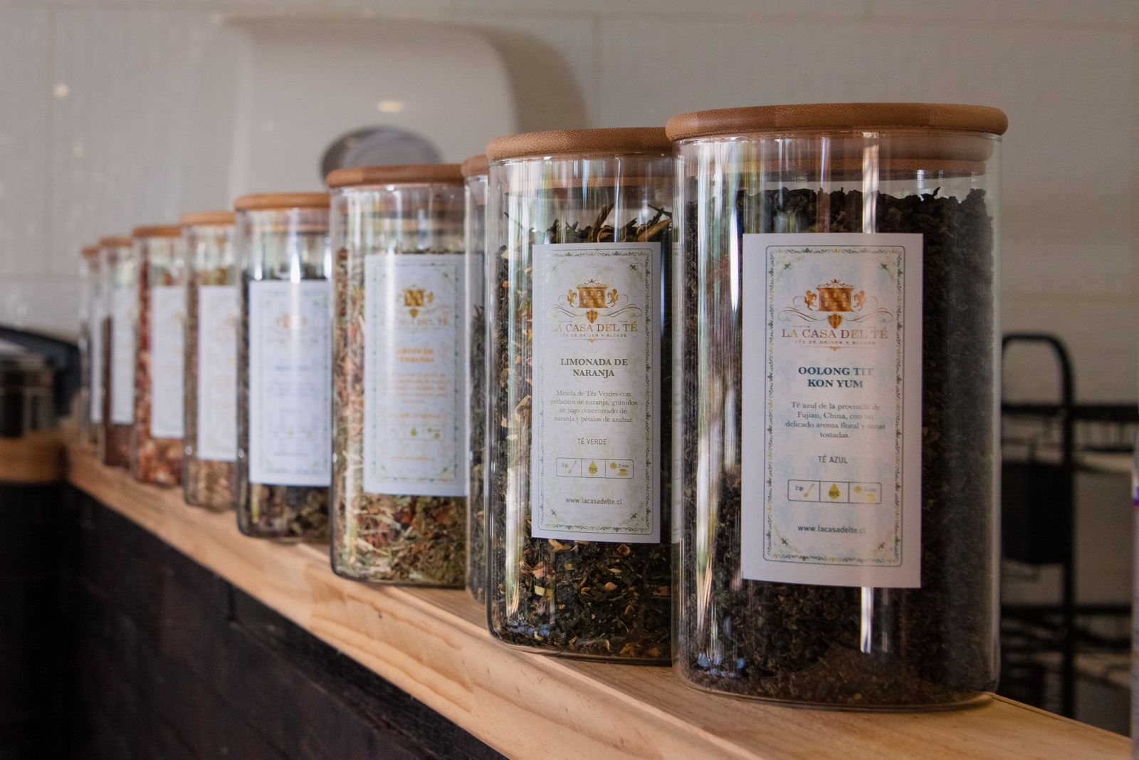 Tall glass jars of loose-leaf tea lined up on a wooden counter
