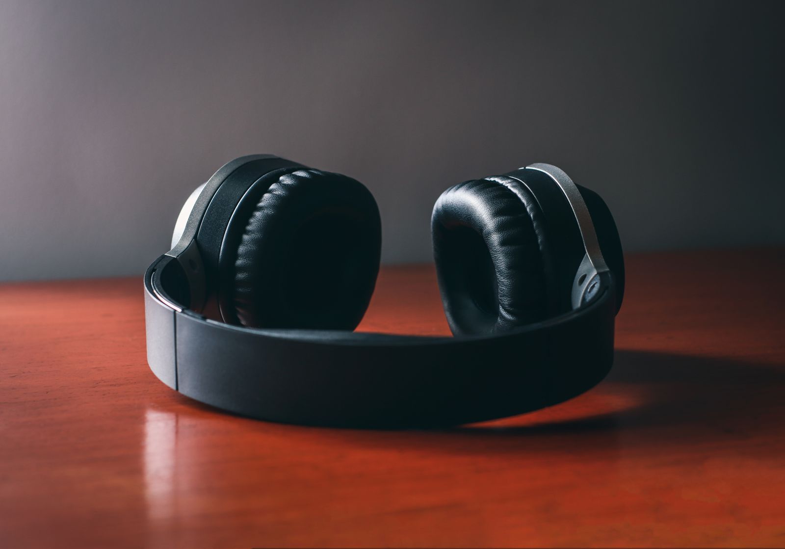 Black over-ear headphones resting on a polished wooden table